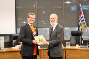 School Board Chair Rob McFarland receives a copy of Canucks in Khaki from Langley Heritage Society Director Jim Foulkes